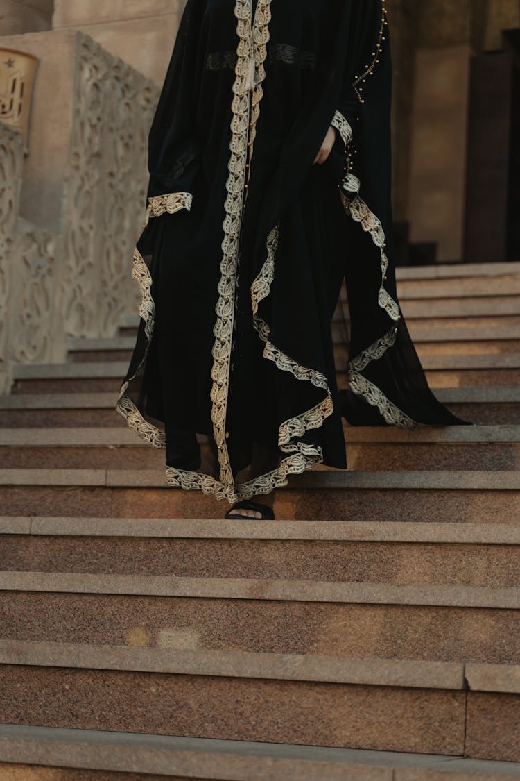 A Person In A Black Robe Walking Down The Stairs