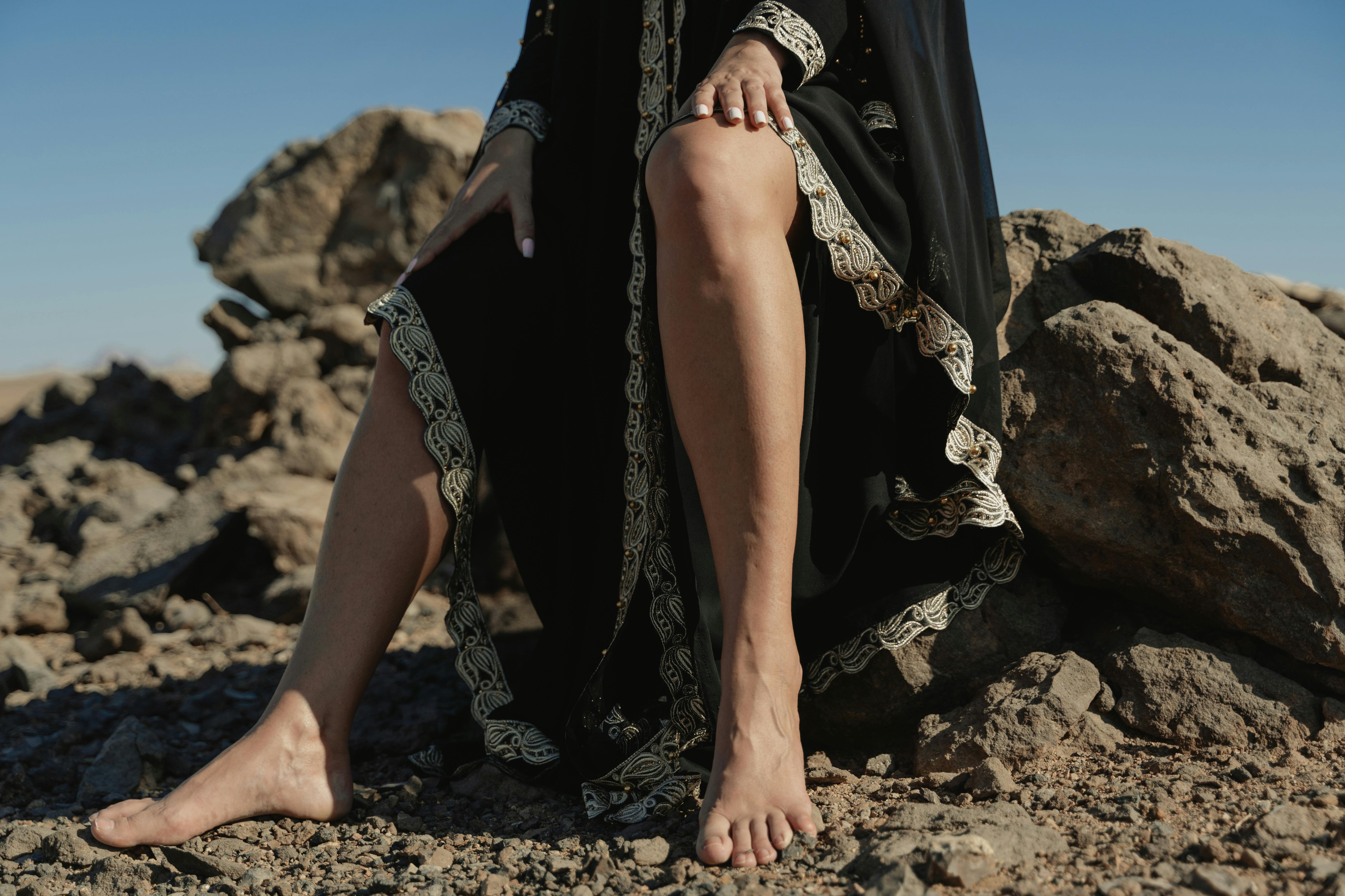 湛蓝的天空下，一个女人穿着长袍坐在岩石上