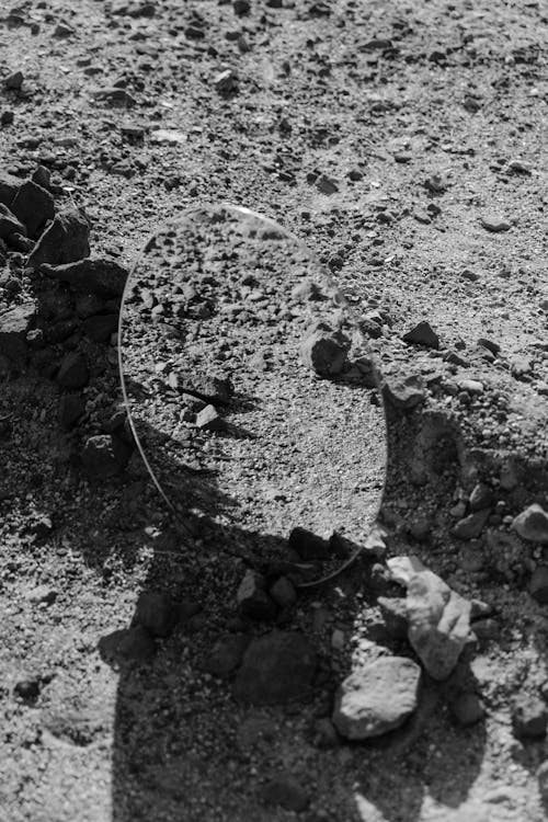 Grayscale Photo of a Mirror on Rocky Ground