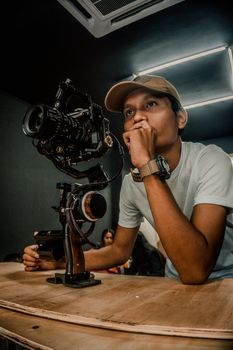 A focused young man operates a gimbal with camera indoors, showcasing modern videography.