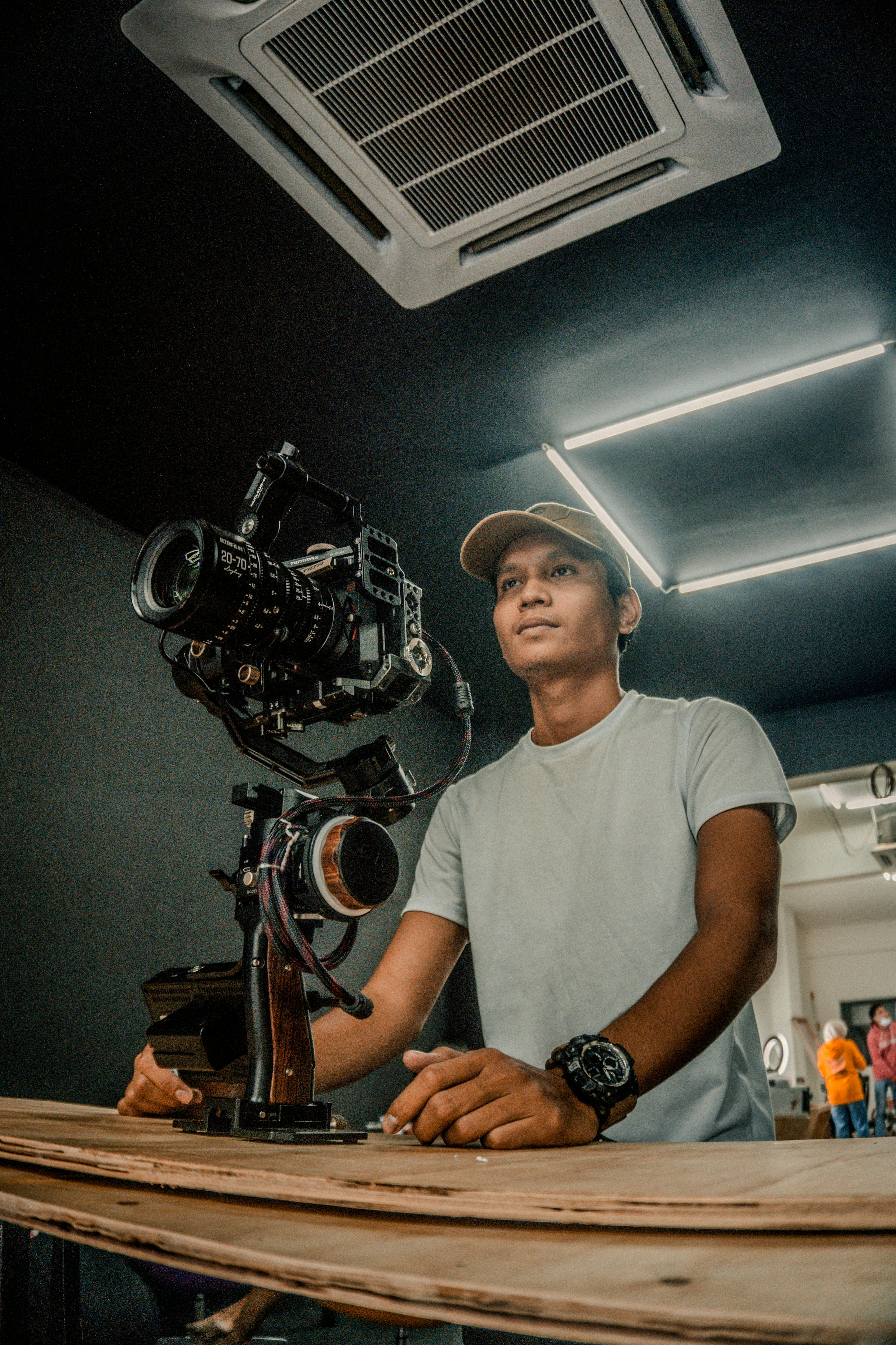 Portrait of a man operating a gimbal camera in a professional studio setting.