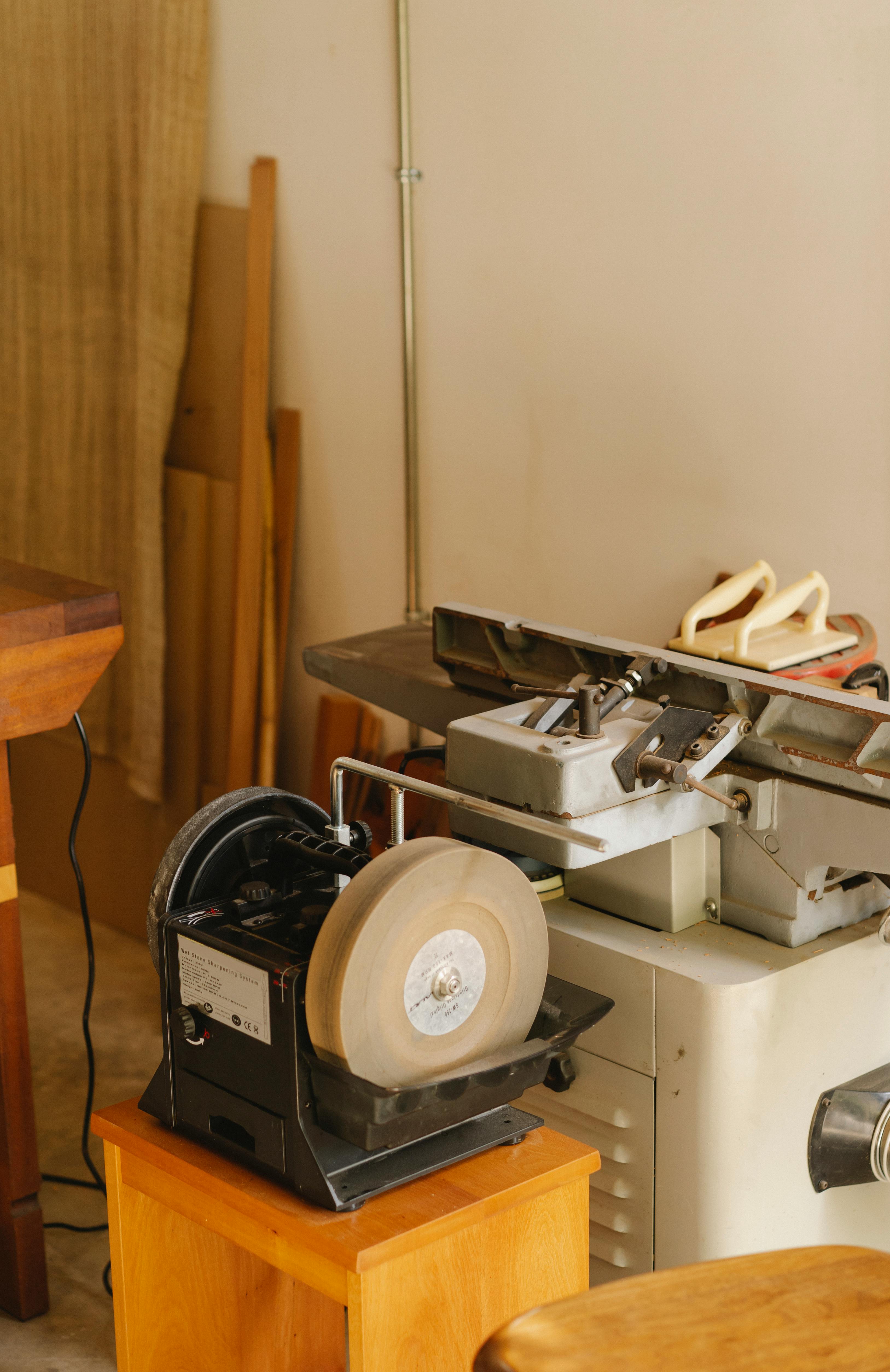 Grinder near wooden planks in light workshop
