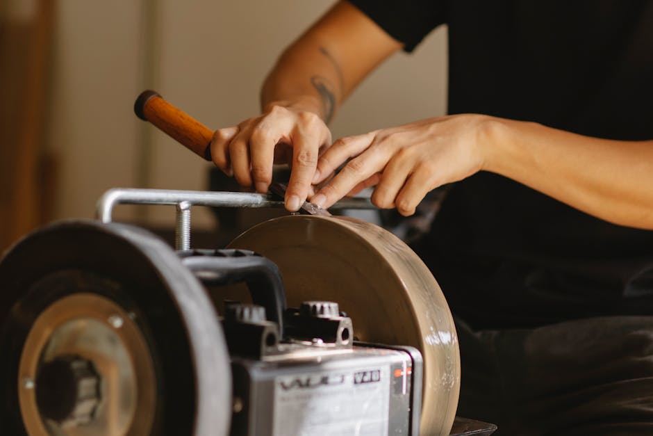 implementing a rolling forecast system - Unrecognizable male master with tattoo sharpening metal detail on grinding wheel while sitting at instrument in professional workshop on blurred background