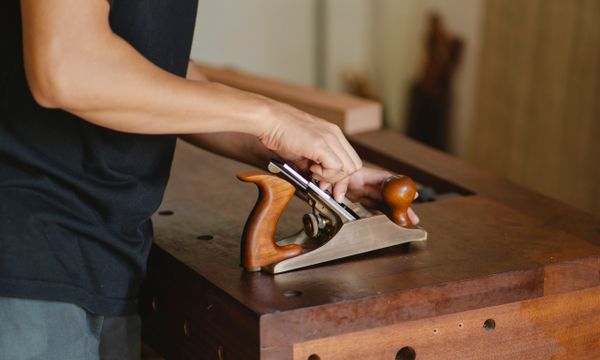 Carpenter working a board through a jointer, photo by Ono Kosuki on Pexels