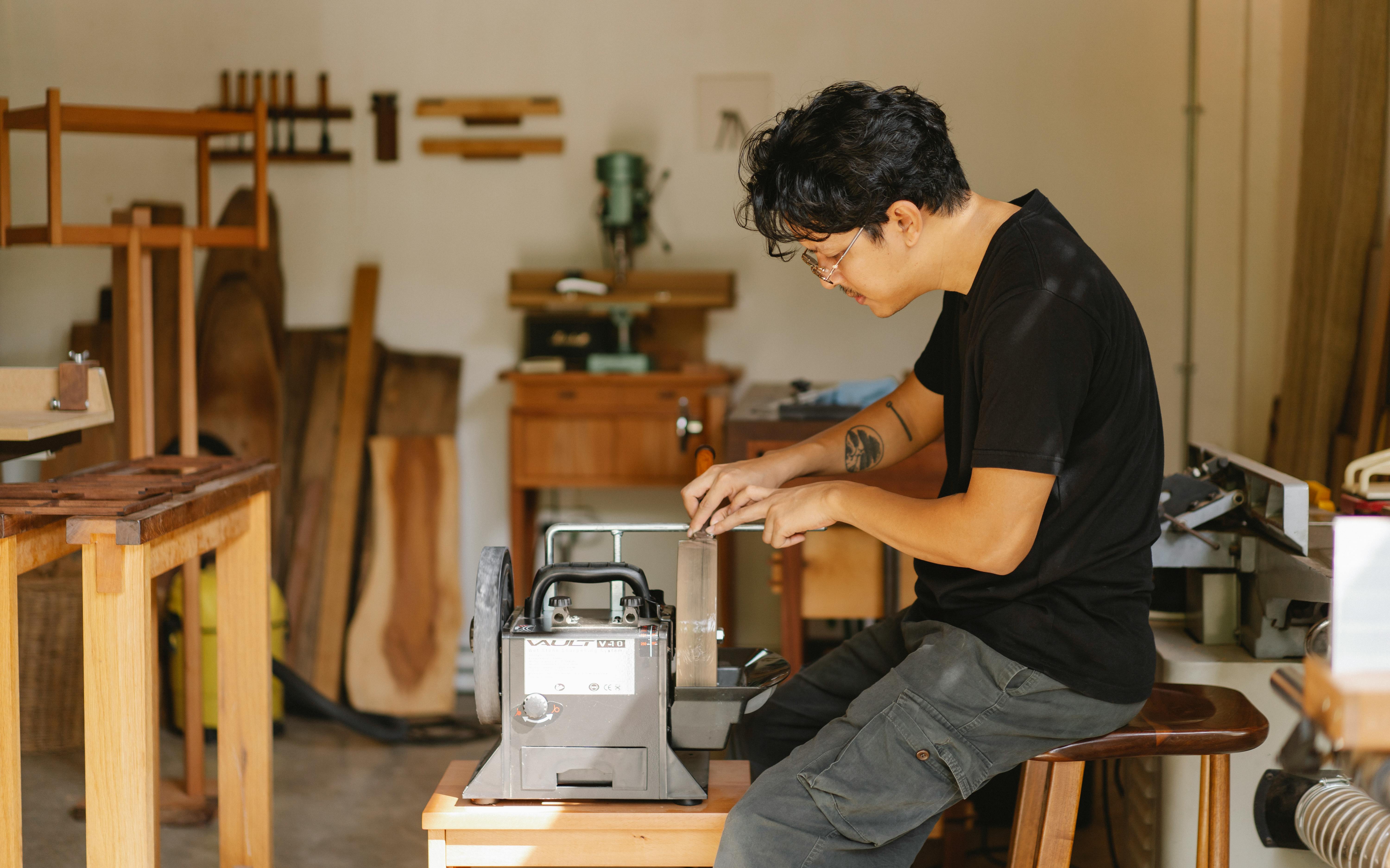 professional ethnic artisan sitting at sharpening tool