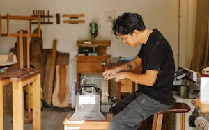 Professional ethnic artisan sitting at sharpening tool