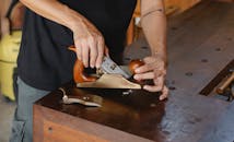 Anonymous male carpenter with tattoo adjusting knife in planer for cutting wood during work in professional workshop on blurred background