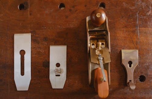 Top view composition of professional planer with wooden handles placed on workbench with set of metal knives in carpentry workshop