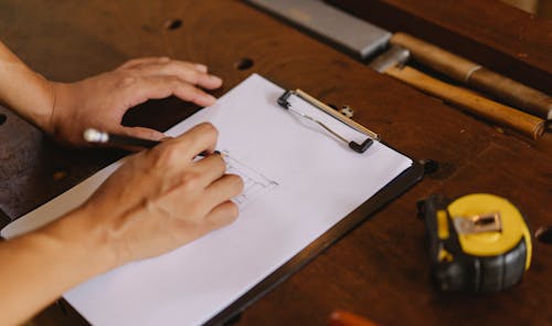 Crop man taking note on clipboard