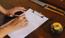 Crop man taking note on clipboard