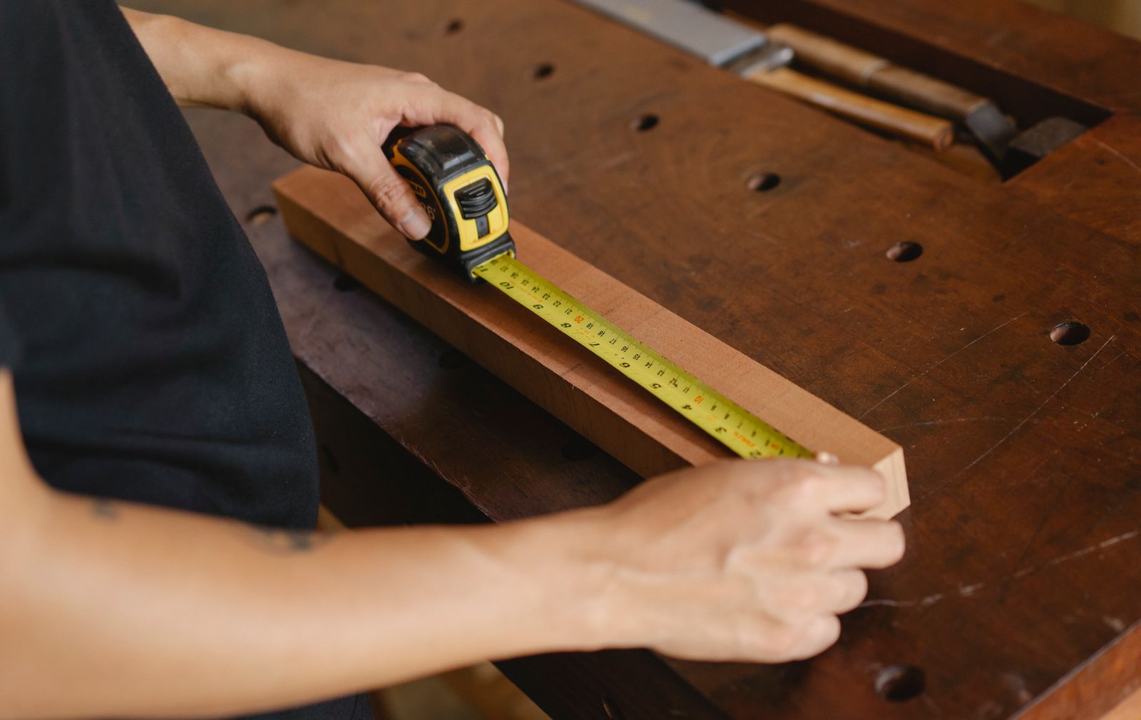 Yellow tape measure and precision woodworking tools arranged on a bright workshop bench