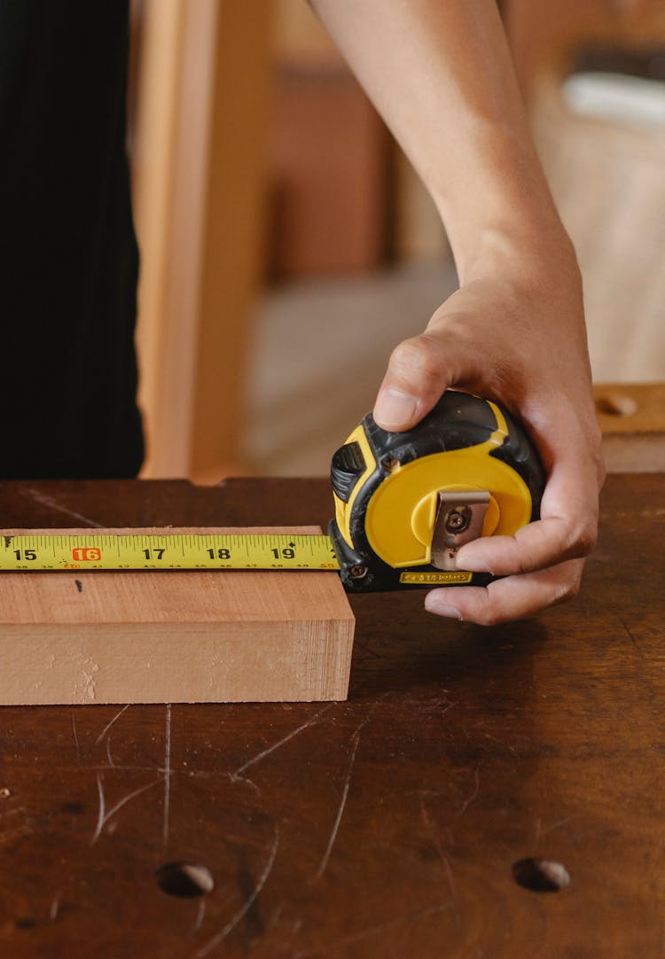 Crop Man Measuring Length Of Plank