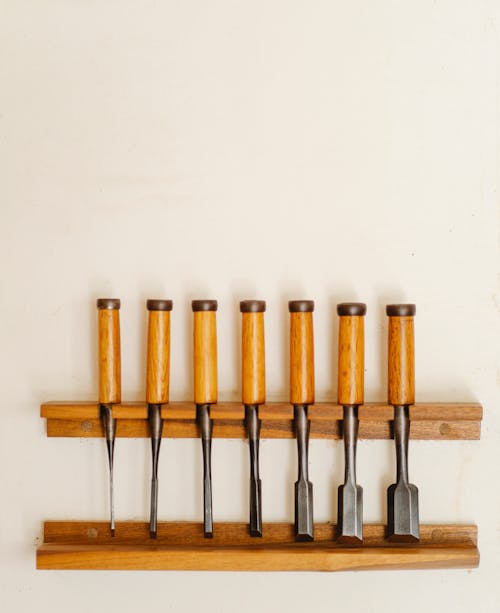 Set of assorted metal wood cutters with different nozzles for woodwork placed on wooden shelf on white background in professional studio