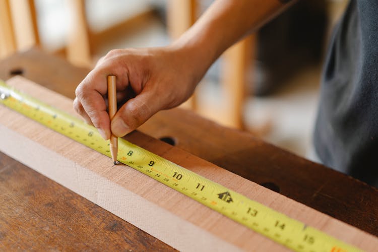 Man Working With Measurement Yellow Tape On Wooden Plank