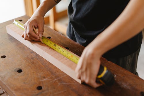 Free Man measuring wooden plank with measurement tape Stock Photo