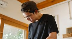 From below of pensive focused ethnic male in eyeglasses and cap doing job in modern workroom