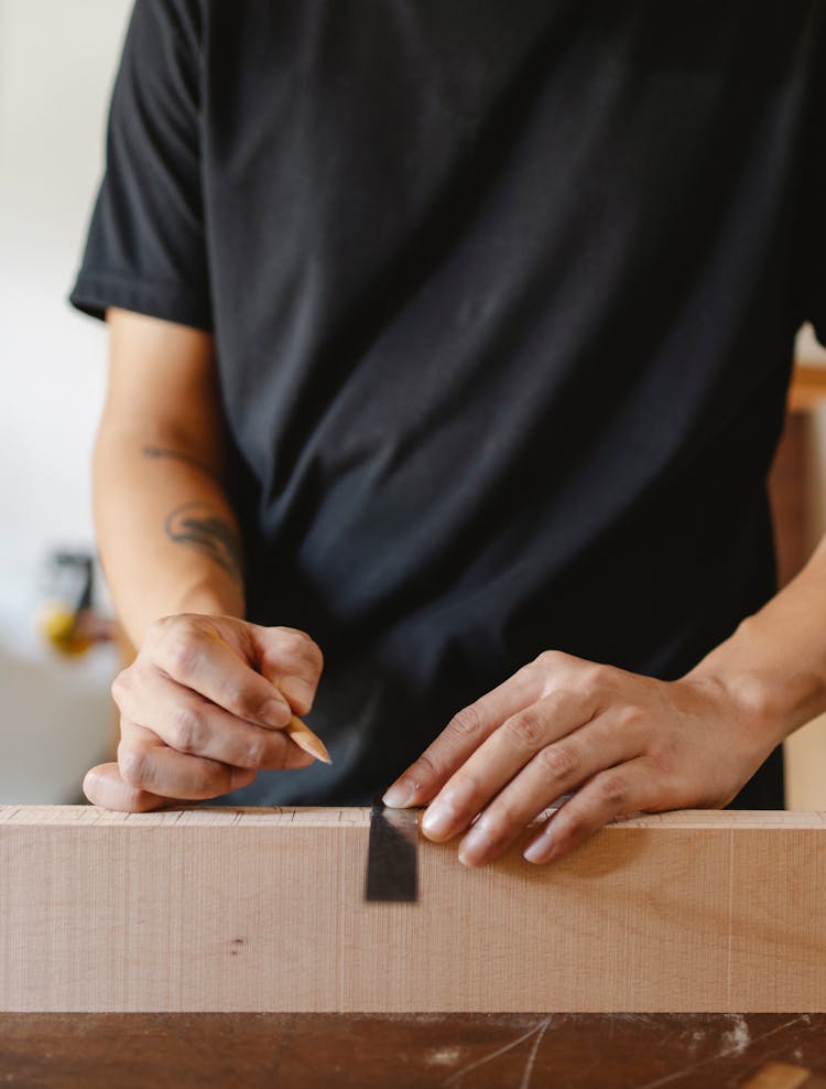 Man Doing Measurement With Ruler On Wooden Plank