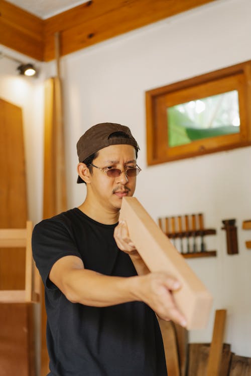 Adult Asian man in eyeglasses examining wooden plank