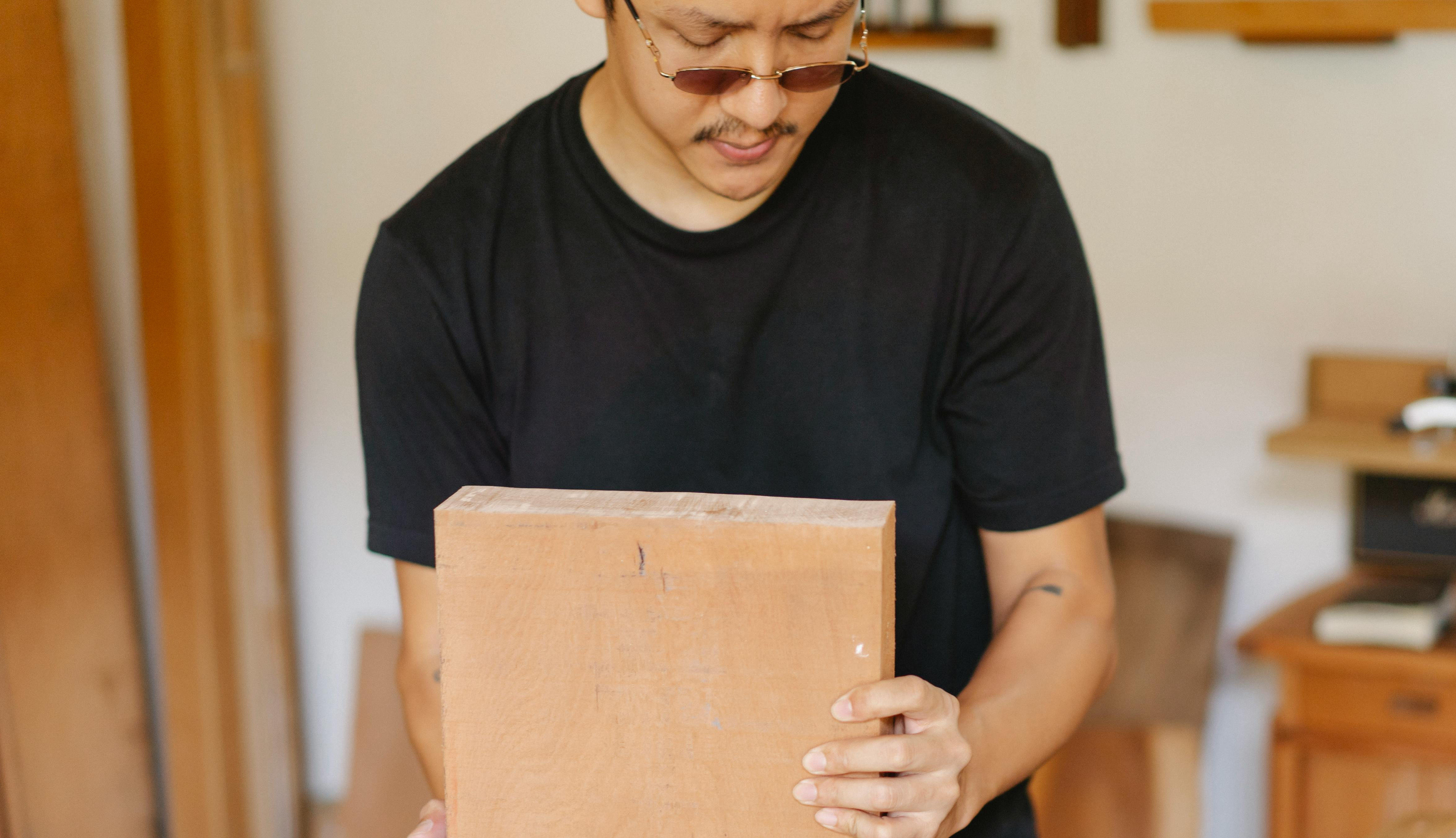 asian joiner in eyeglasses installing wooden plank