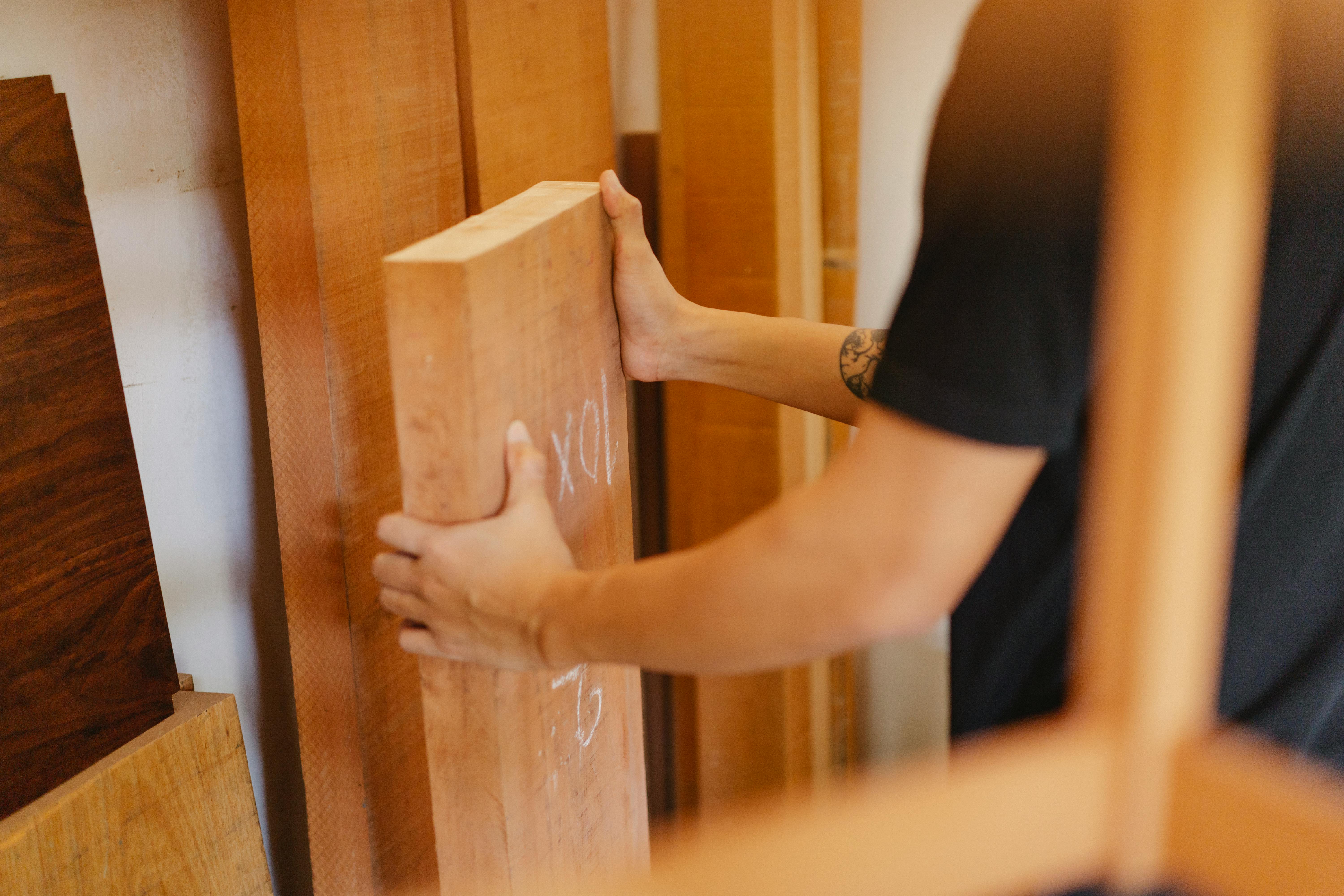 man picking wooden plank from store