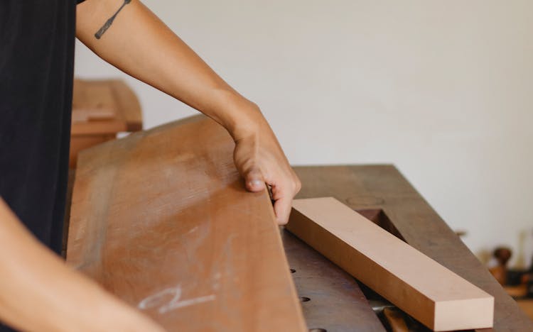 Man Working With Heavy Wooden Plank In Joinery Studio