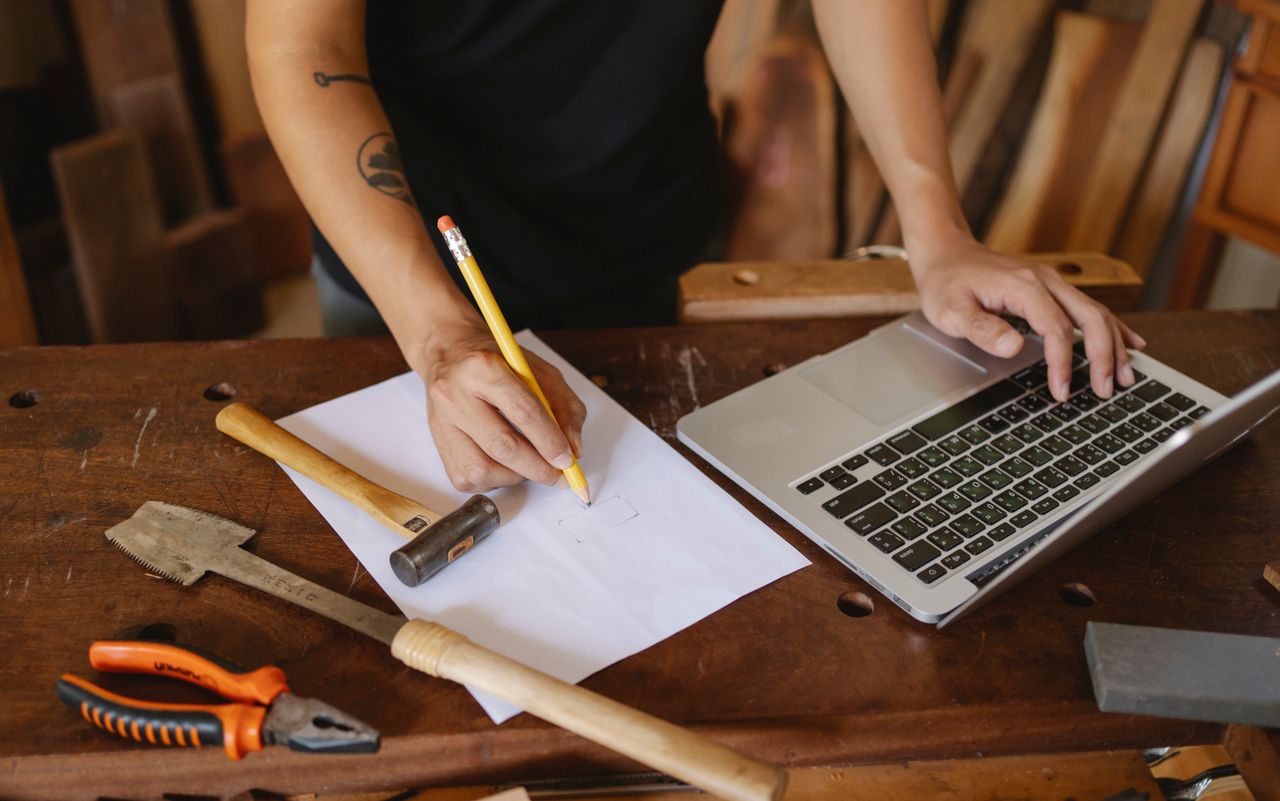 crop faceless male worker standing near table and creating new craft p