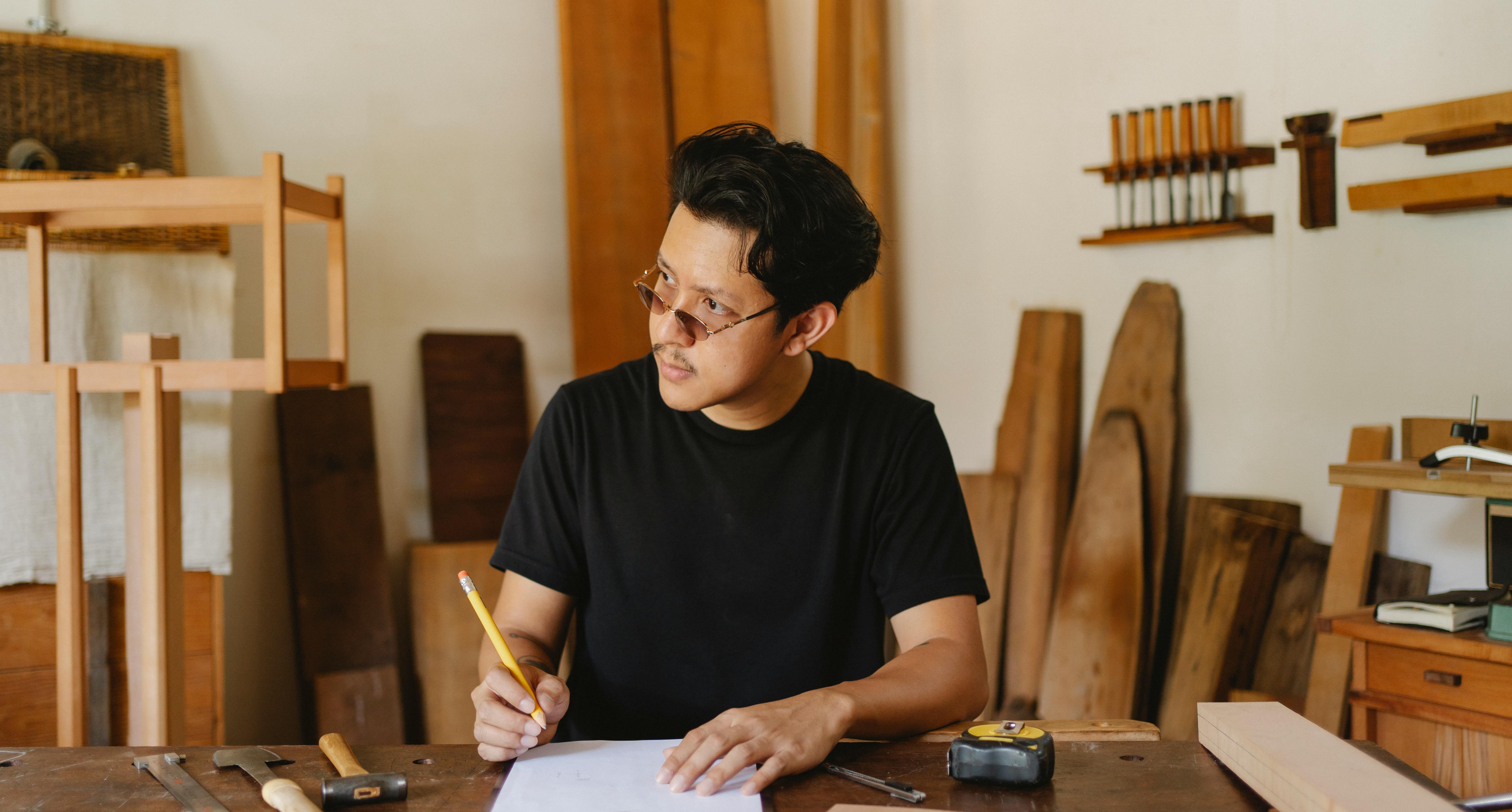 thoughtful asian man creating project in joinery