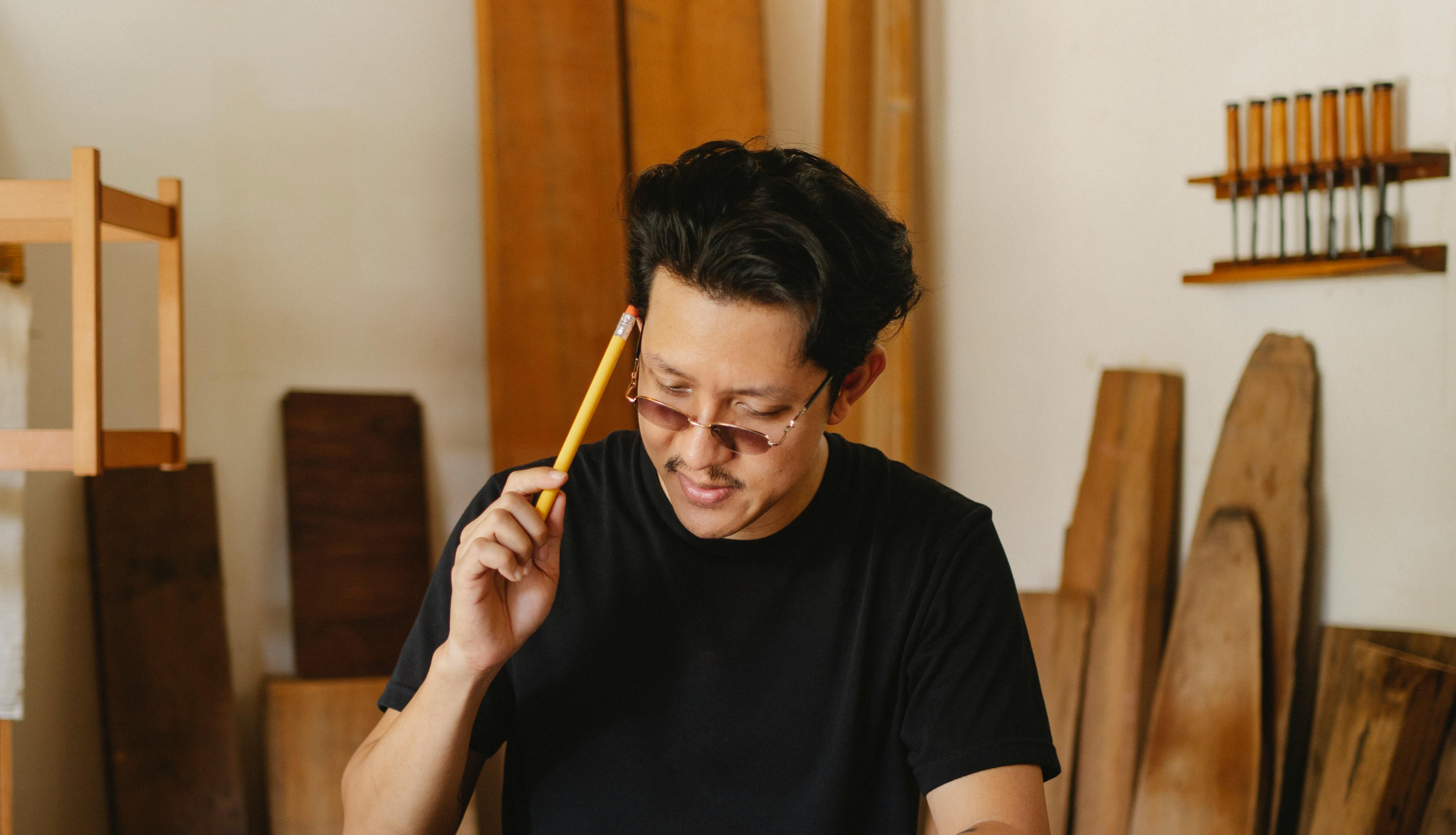 focused asian man with pencil in workshop