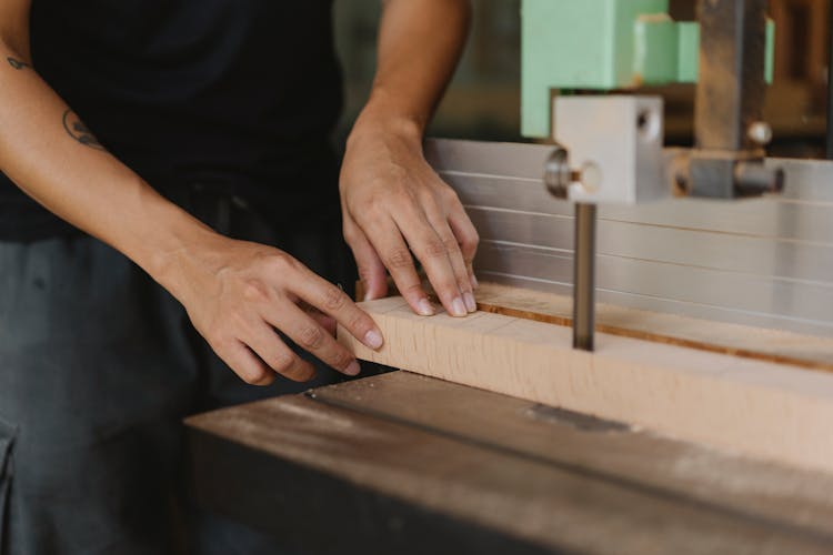 Crop Carpenter Cutting Wooden Plank With Band Saw In Workshop