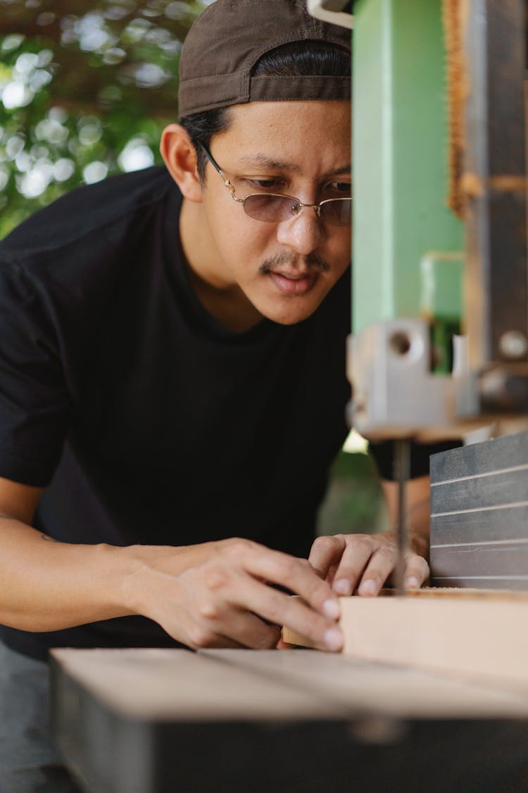 Crop Attentive Asian Carpenter Sawing Timber With Band Saw