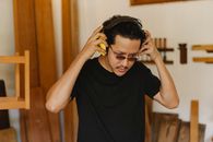 Pensive Asian carpenter putting on headphones in workroom