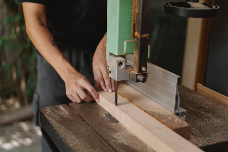 Faceless Carpenter Cutting Timber With Band Saw On Table