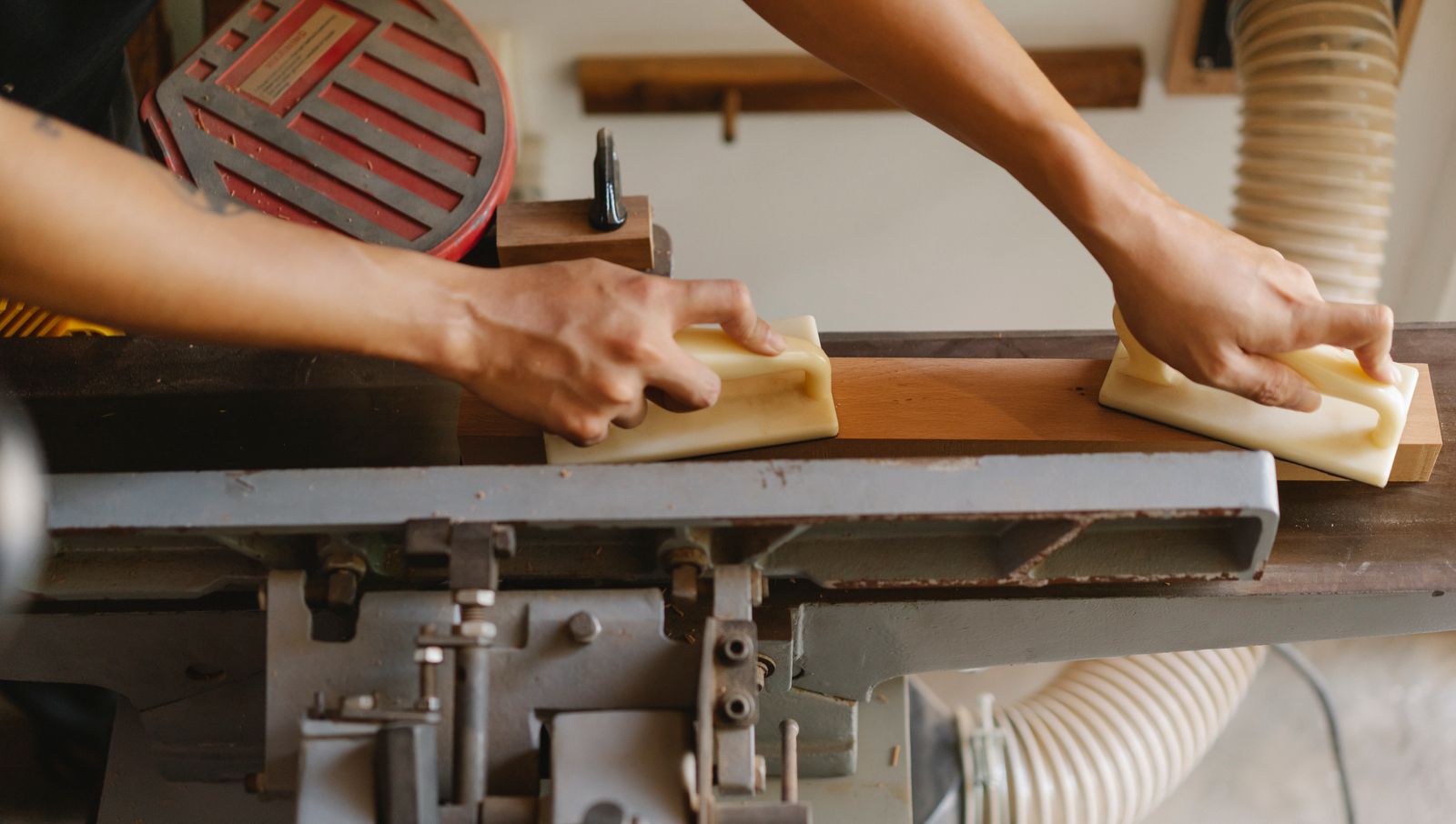 From above of crop anonymous woodworker leveling timber on professional equipment using manual instruments in workroom i