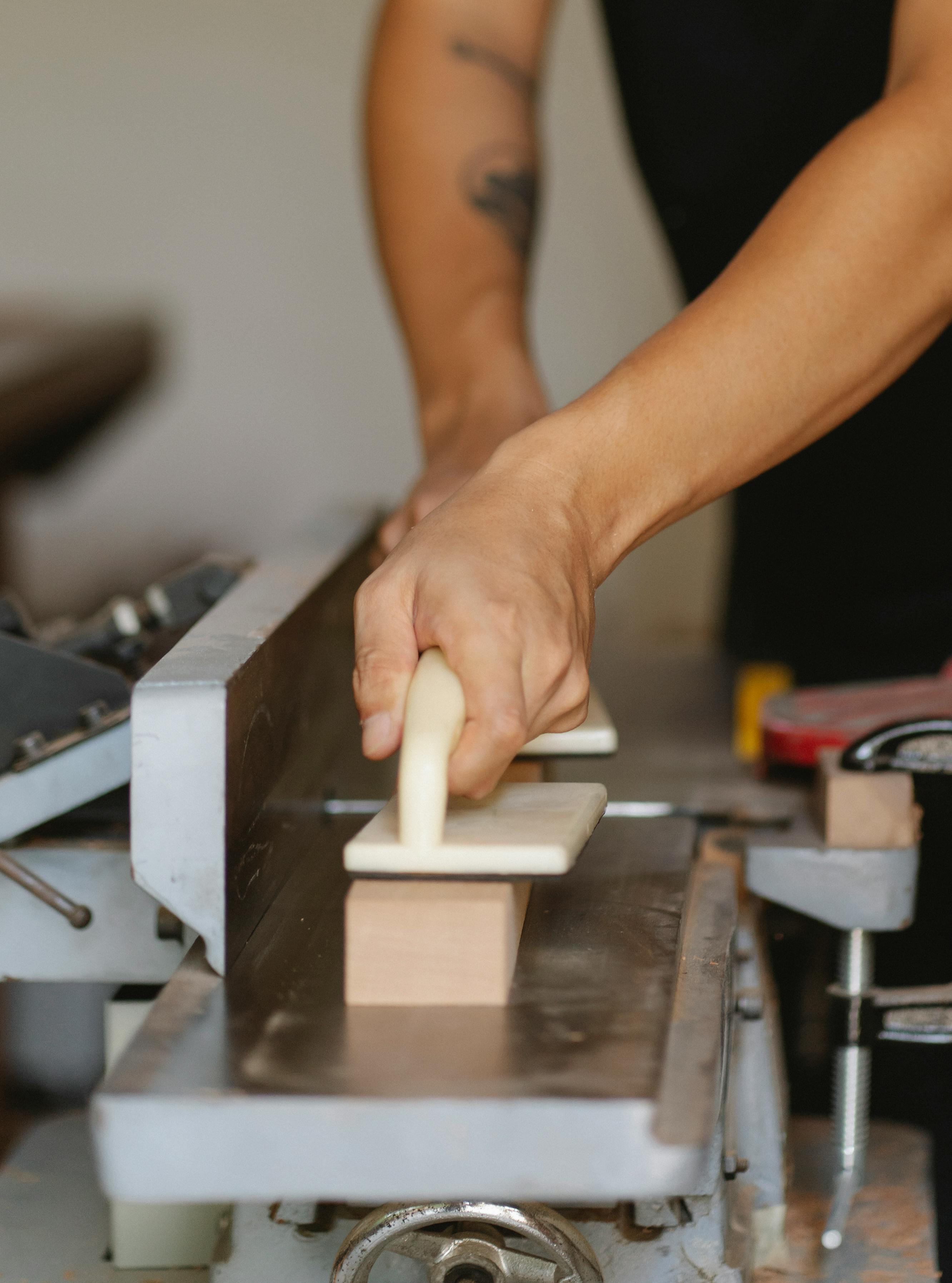 faceless artisan leveling lumber on jointer in workroom