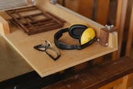 From above of noise cancelling headphones with protective glasses for joinery on wooden table in workroom