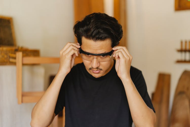 Serious Asian Carpenter Putting On Protective Glasses In Workshop