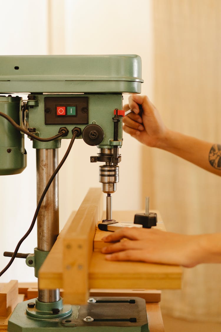 Faceless Artisan Working With Drill Press In Workroom