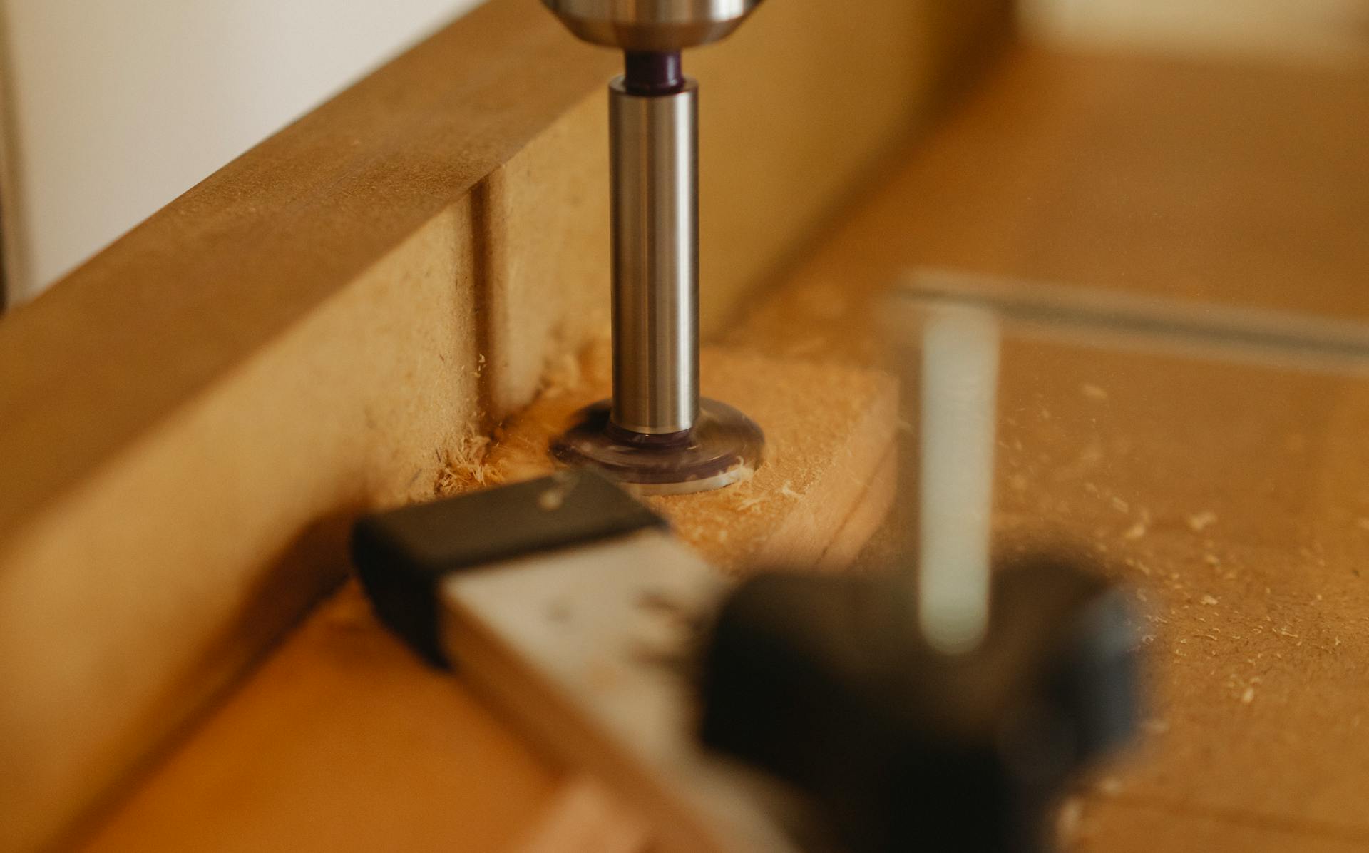 Detailed image of a woodworking router in action, shaping a wooden plank in a contemporary workshop.