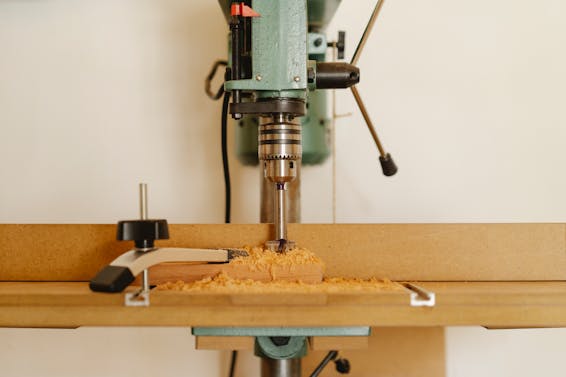 Professional drill machine for cutting wooden details near white wall in modern workshop