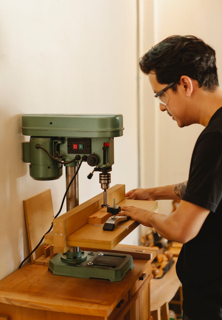 Craftsman Drilling Hole With Drill Press In Workshop