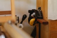 Yellow noise cancelling headphones for carpentry work hanging on timber shelf in workshop