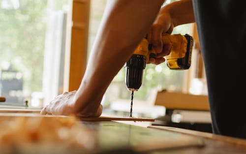 Free Man drilling wooden plank on desk Stock Photo