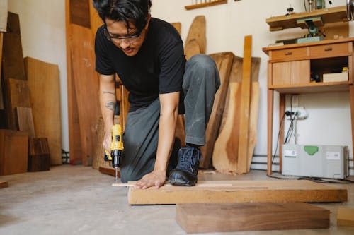 Free Ethnic man leaning on wooden plank and drilling hole Stock Photo