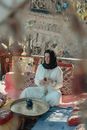 Woman in White Long Sleeve Shirt Sitting on Red and White Floral Sofa