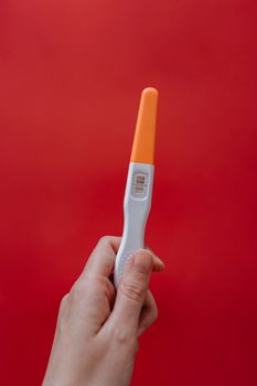 在充满活力的红色背景下，一张阳性妊娠试纸的特写，象征着喜悦和新的开始