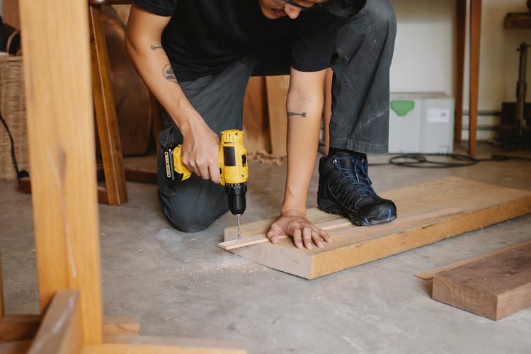 Man Drilling Piece Of Wooden With Screwdriver