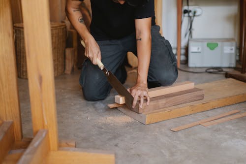 Crop man cutting wood in workshop