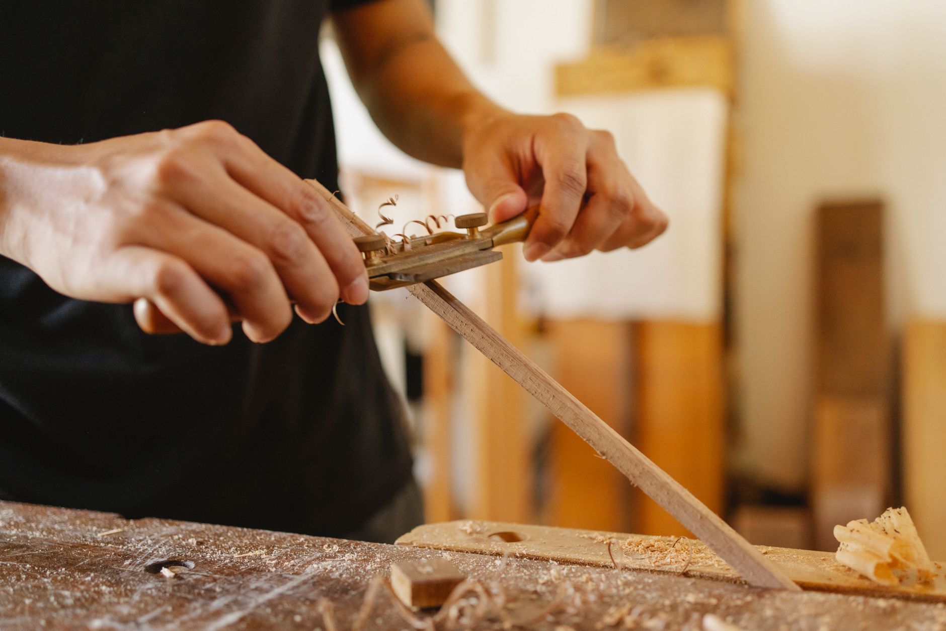 Craftsman planing timber in a bright studio