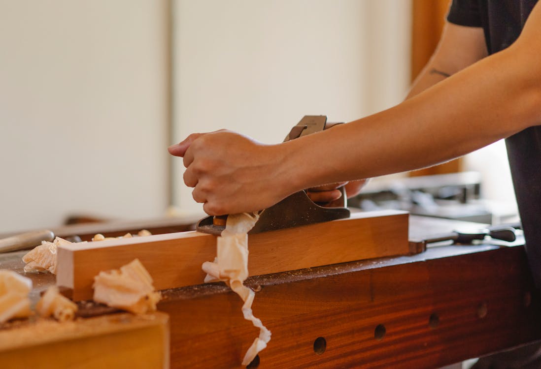 Crop woodworker planing hardwood plank