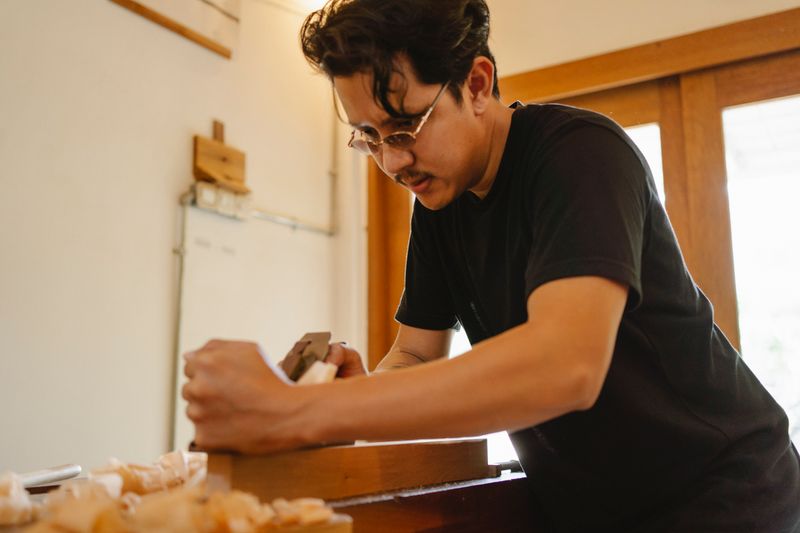 Artisan carpenter focused on precision woodwork in a well-lit workshop — the craft behind every custom millwork project